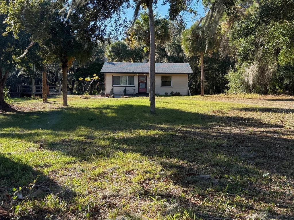 A single-story house with light siding sits on a grassy lot surrounded by trees — 3258 S RIDGEWOOD AVENUE, EDGEWATER, FL