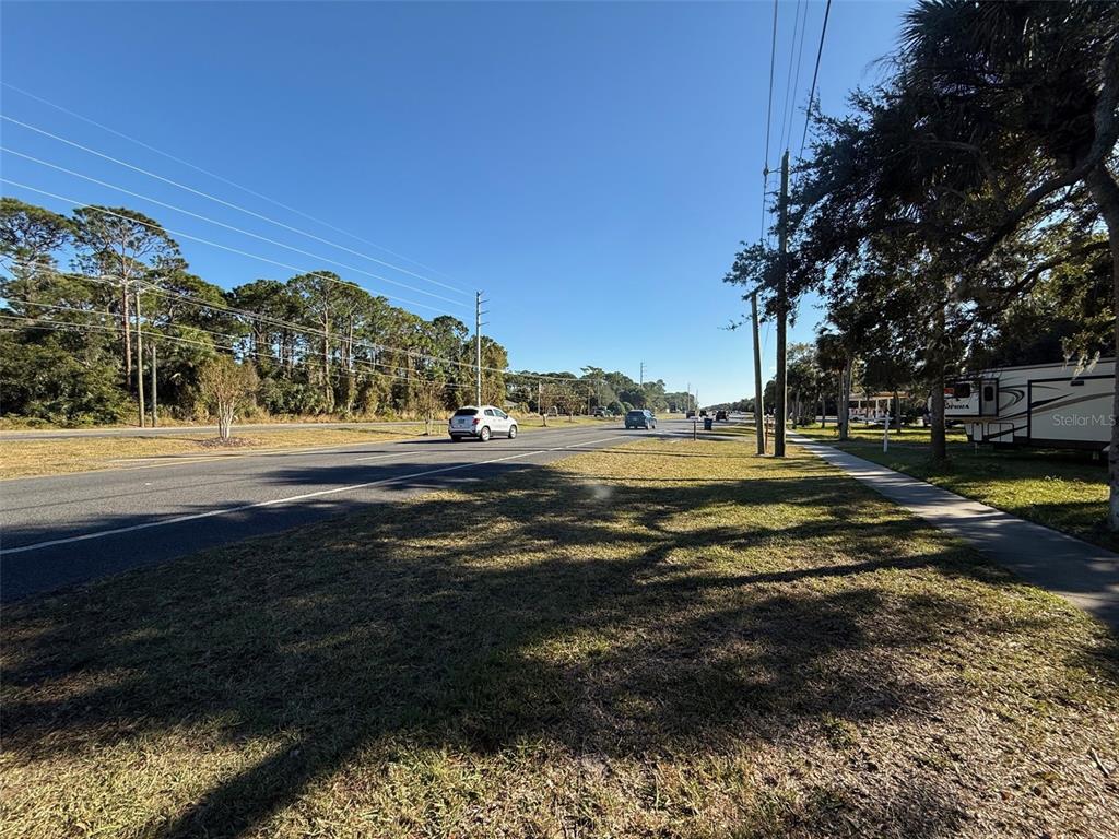 A view of a paved road with cars and trees alongside a grassy shoulder — 3258 S RIDGEWOOD AVENUE, EDGEWATER, FL