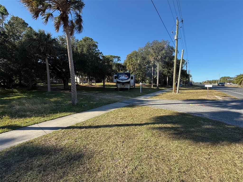 A recreational vehicle is parked on a grassy lot next to a sidewalk and road — 3258 S RIDGEWOOD AVENUE, EDGEWATER, FL