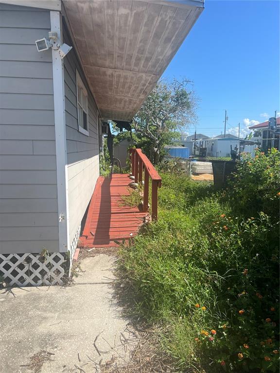 A wooden wheelchair ramp leads along the side of a gray house with lattice skirting — 6731 FLICKER LANE, HUDSON, FL