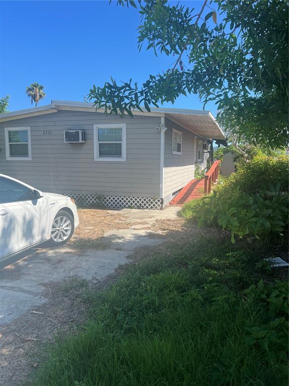 A light gray mobile home features a white car parked on a concrete driveway — 6731 FLICKER LANE, HUDSON, FL