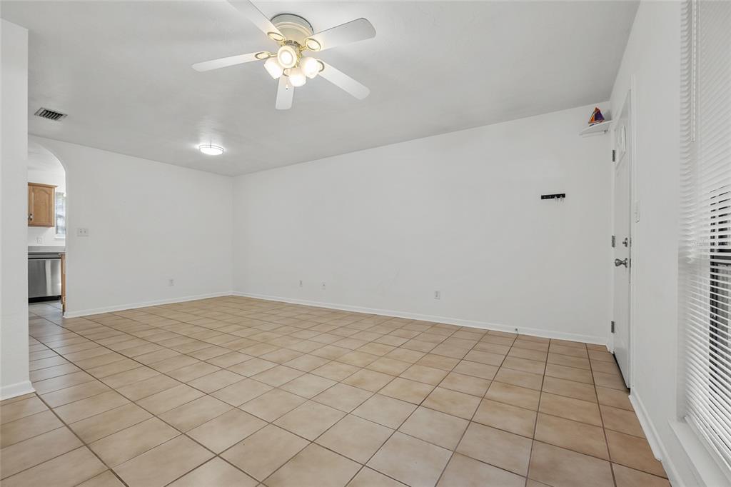 A living room with white walls, a ceiling fan, and light-colored square floor tiles — 4219 NW 30TH TERRACE, GAINESVILLE, FL