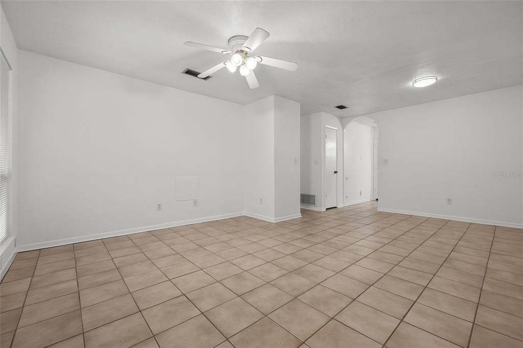An empty room features white walls, tan tile flooring, and a ceiling fan with lights — 4219 NW 30TH TERRACE, GAINESVILLE, FL
