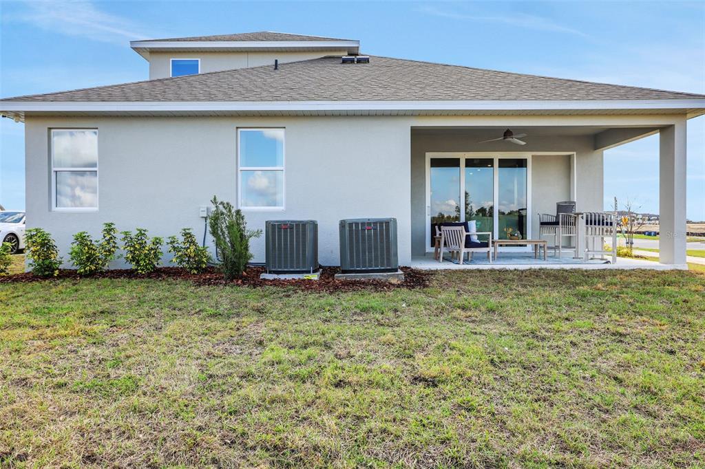 The exterior rear view of a house features a covered patio and two HVAC units — 5361 SPADERDOCK LANE, APOPKA, FL