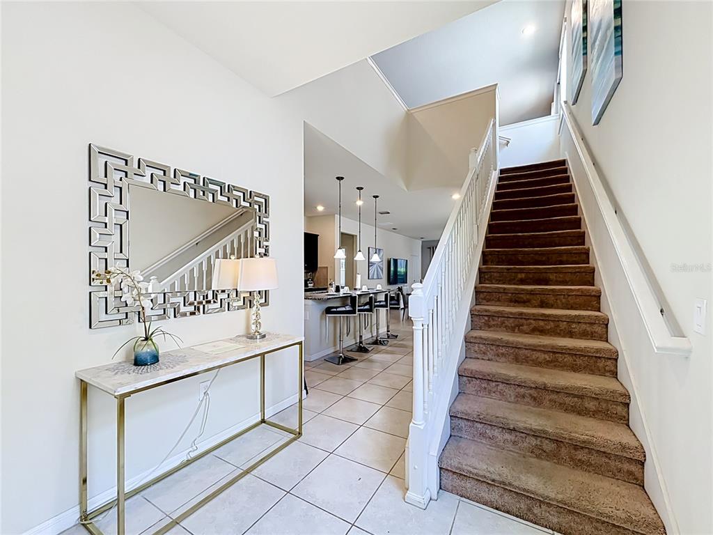 An entryway features a marble-topped console table, a decorative mirror, and a carpeted staircase — 5485 MISTY OAK CIRCLE, DAVENPORT, FL