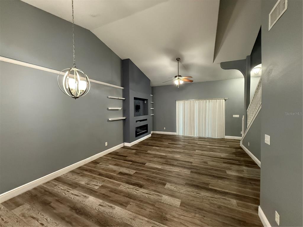 A living room features gray walls, wood-look flooring, a fireplace, and a vaulted ceiling — 8927 COURTYARD LANE, GROVELAND, FL