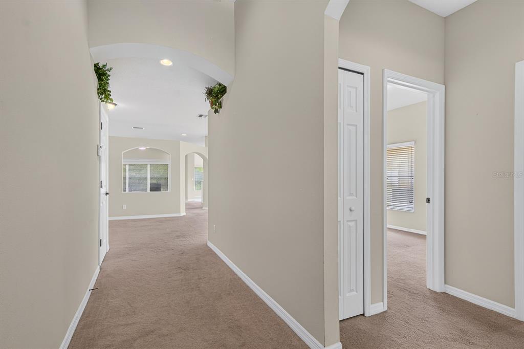 A carpeted hallway leads to an open living area with arched architectural details — 11231 BELLE HAVEN DRIVE, NEW PORT RICHEY, FL