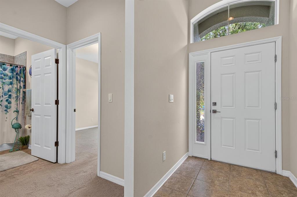 An entryway features a white front door with a sidelight, tile flooring, and two doorways — 11231 BELLE HAVEN DRIVE, NEW PORT RICHEY, FL