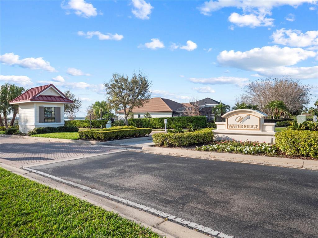 The entrance to the Waterridge community features a gatehouse, landscaping, and a stone monument sign — 535 ADAMS VIEW LANE, AUBURNDALE, FL