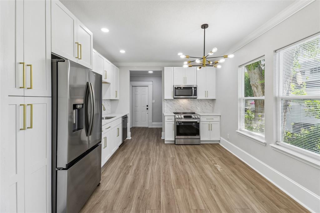 A modern kitchen features white cabinets, gold hardware, marble-look countertops, and light wood flooring — 43 W MURIEL STREET, ORLANDO, FL