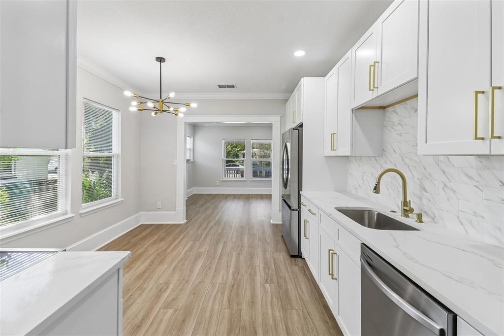 A modern kitchen features white shaker cabinets, stainless steel appliances, and a marble-patterned tile backsplash — 43 W MURIEL STREET, ORLANDO, FL