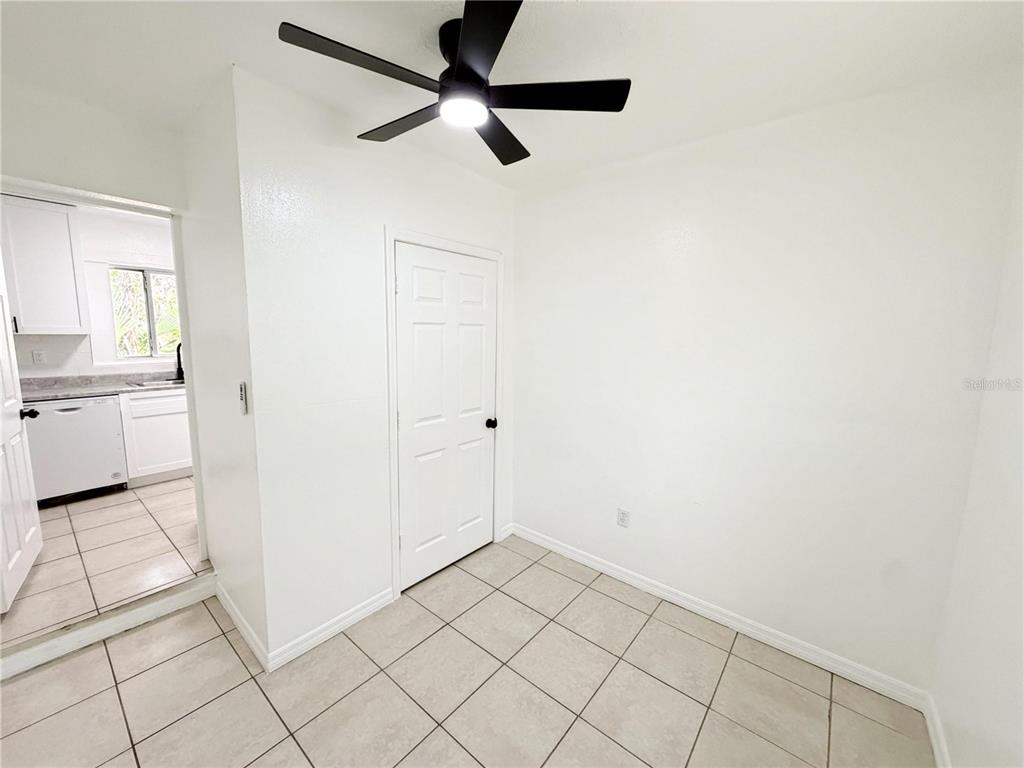 A room with white walls, tile flooring, a ceiling fan, and a closed door — 3916 E GENESEE STREET, TAMPA, FL