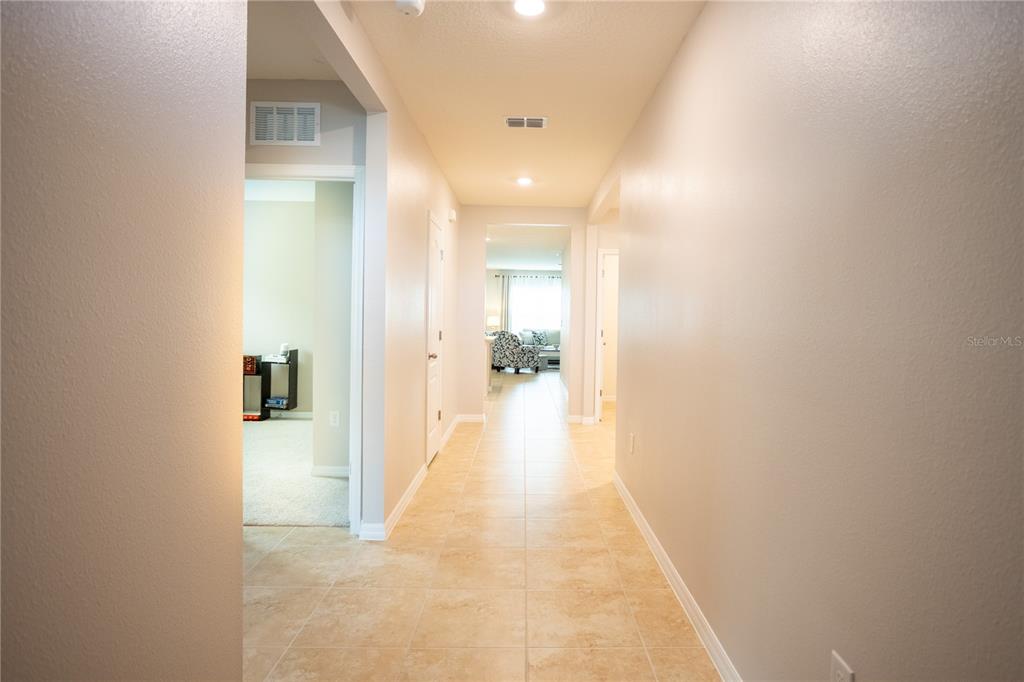 A tiled hallway leads to a living area with light-colored walls and recessed lighting — 2791 HOUSE FINCH ROAD, ST CLOUD, FL