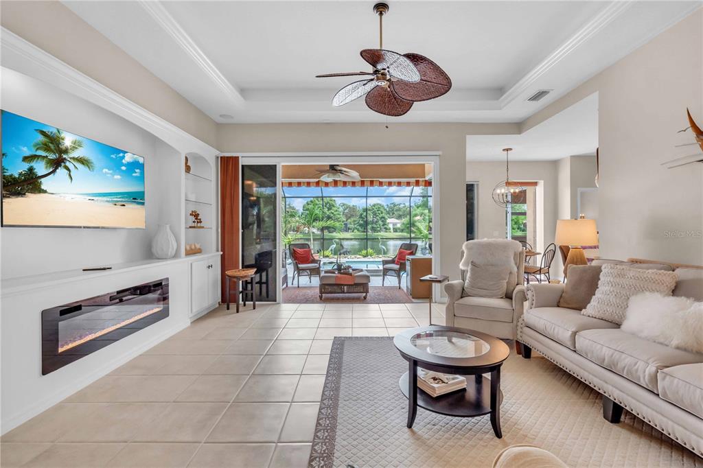 A living room features a fireplace, built-in shelving, a ceiling fan, and sliding glass doors — 521 HABITAT BOULEVARD, OSPREY, FL