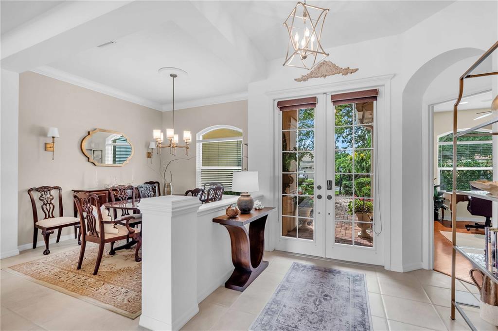 A bright foyer with a half-wall divider leads into a dining room with glass doors — 521 HABITAT BOULEVARD, OSPREY, FL