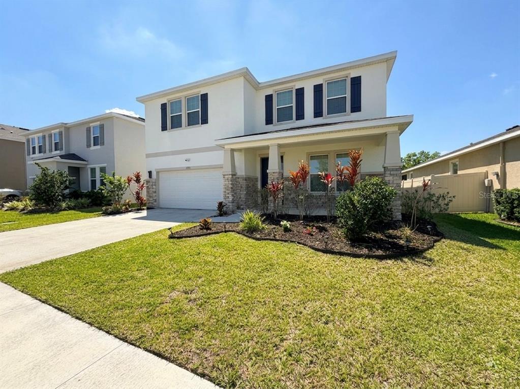 A two-story suburban house with a white stucco facade, stone accents, and a front lawn — 16910 OVAL RUM DRIVE, WIMAUMA, FL