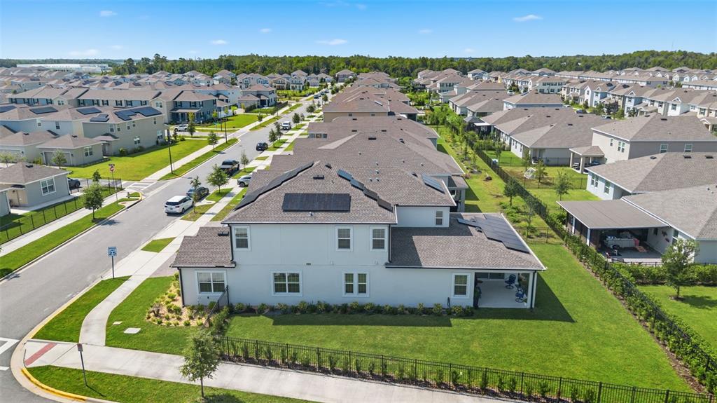An aerial view shows a two-story suburban house with solar panels and a fenced yard — 11502 PARAGRAPH ROAD, ORLANDO, FL