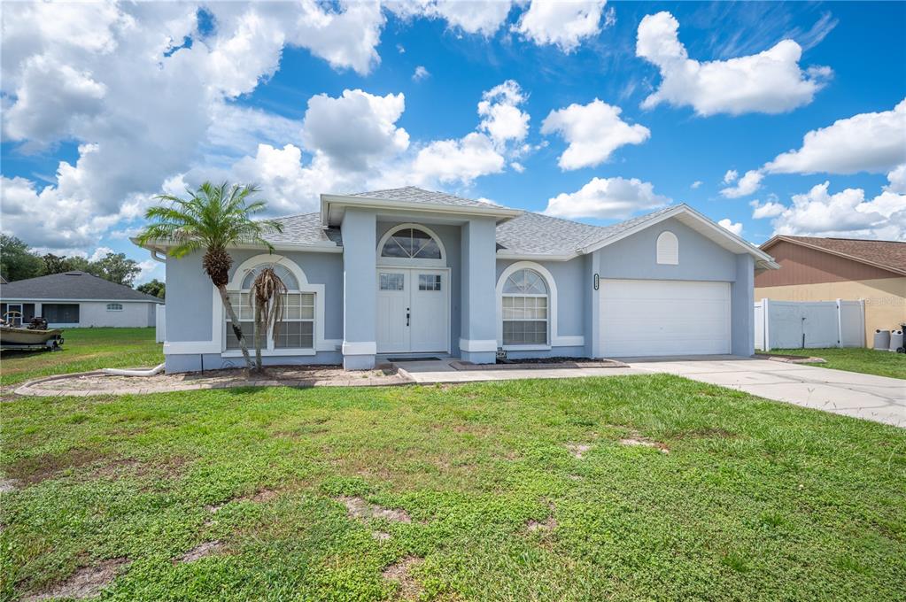 A single-story light blue house with a white double front door and a two-car garage — 3326 MERLOT DRIVE, LAKELAND, FL