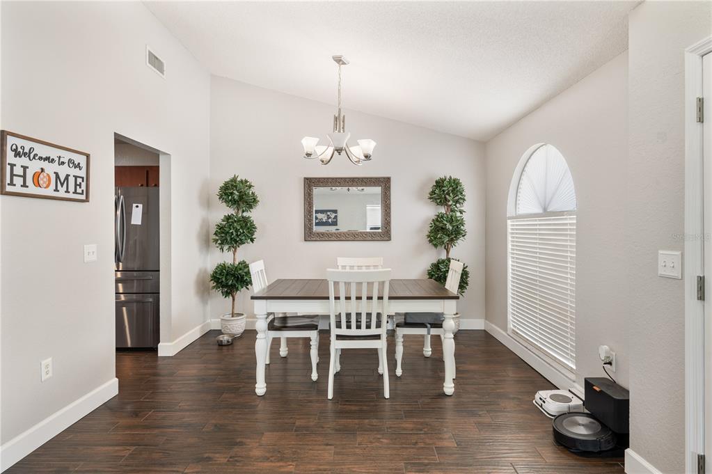 A dining room features a white table, four chairs, a chandelier, and dark wood flooring — 3326 MERLOT DRIVE, LAKELAND, FL