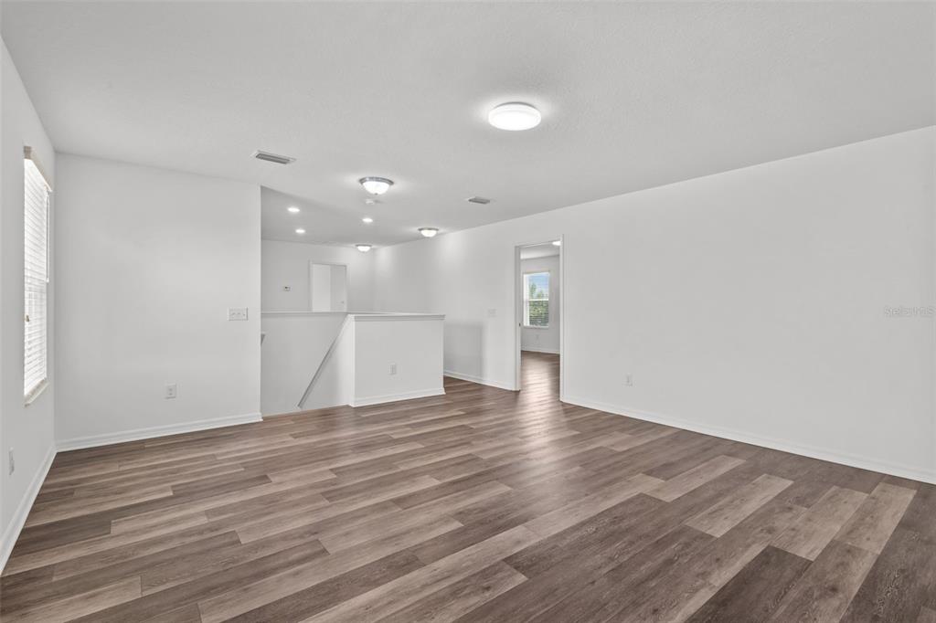An empty room features light gray walls, dark wood-look flooring, and a ceiling fan — 12124 LAKE BOULEVARD, NEW PORT RICHEY, FL