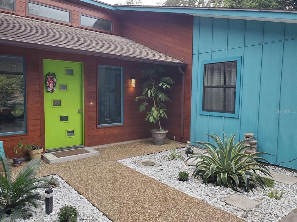 The exterior of a house features a lime green door, wood siding, and blue paneling — 5017 E 127TH AVENUE, TEMPLE TERRACE, FL