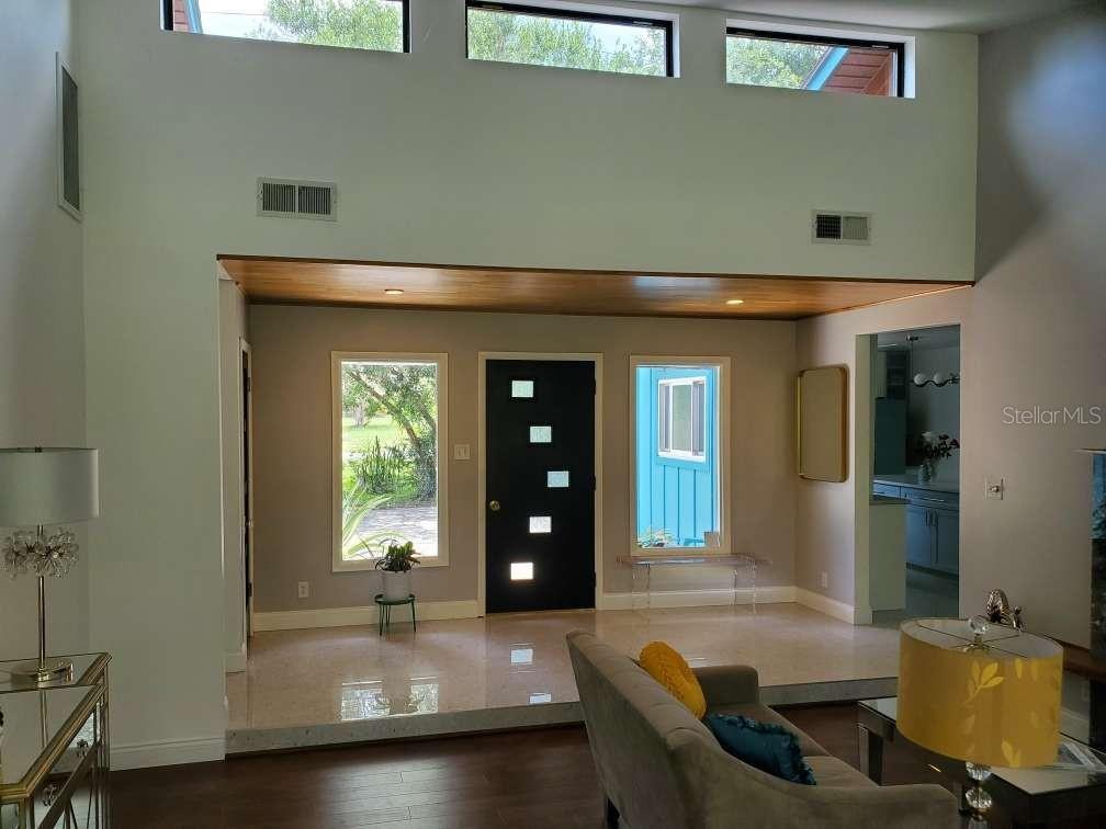 An entryway with a black front door, clerestory windows, and a raised terrazzo floor — 5017 E 127TH AVENUE, TEMPLE TERRACE, FL