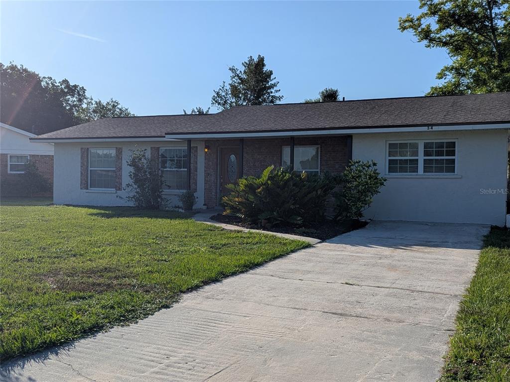 A single-story house with a brick facade, white stucco walls, and a concrete driveway — 34 SEVILLA AVENUE, ARCADIA, FL