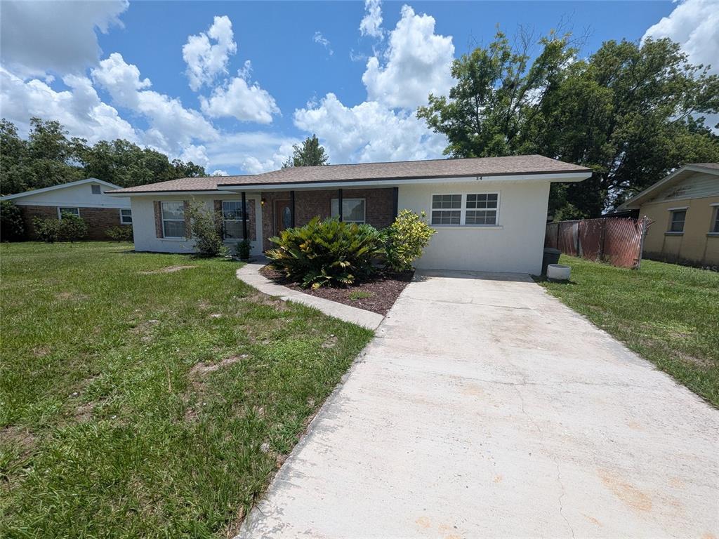 A single-story house with a concrete driveway, a brick facade section, and a front lawn — 34 SEVILLA AVENUE, ARCADIA, FL
