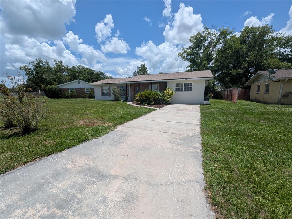 A single-story house with a concrete driveway and a grassy front yard under a cloudy sky — 34 SEVILLA AVENUE, ARCADIA, FL