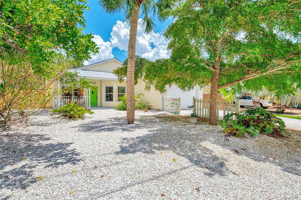 A light-colored house with a bright green front door sits behind a gravel driveway — 5253 AVENIDA DEL MARE, SARASOTA, FL