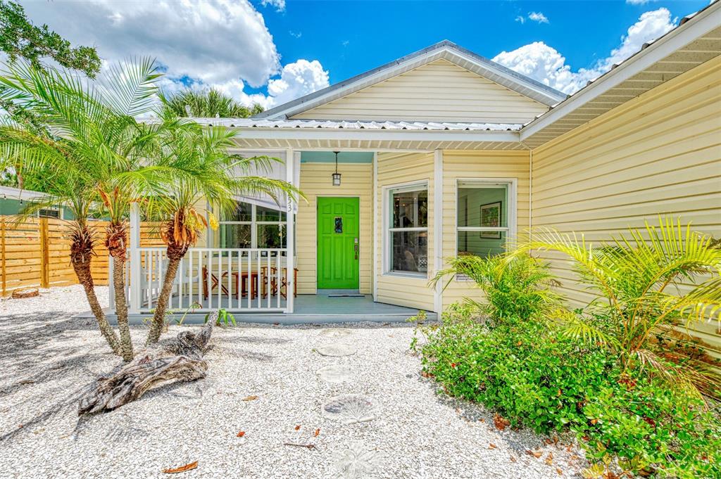 A light yellow house features a bright green front door and a white railed porch — 5253 AVENIDA DEL MARE, SARASOTA, FL