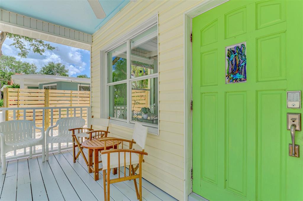 A covered porch features a bright green front door, light yellow siding, and outdoor furniture — 5253 AVENIDA DEL MARE, SARASOTA, FL