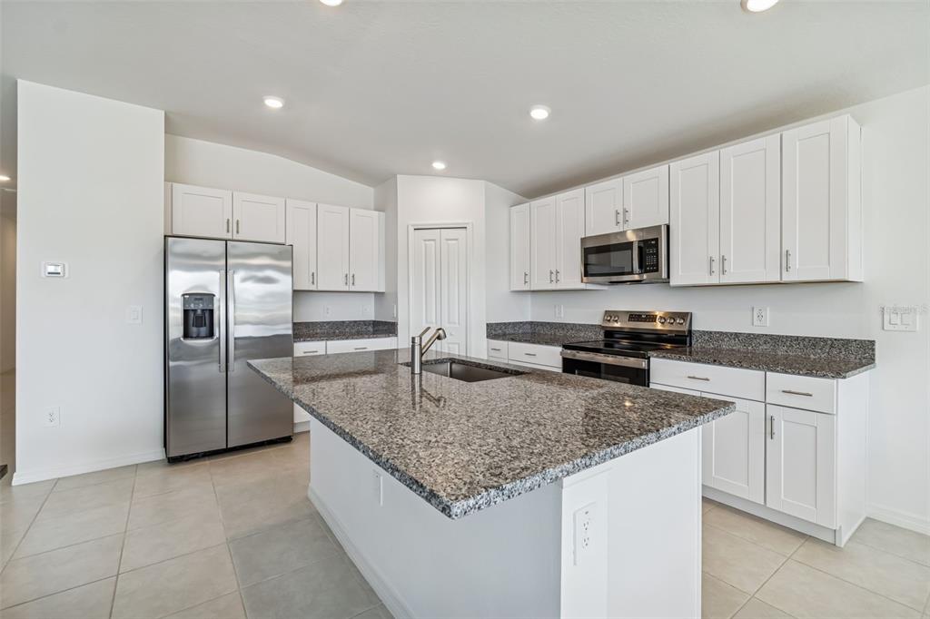 A kitchen with white cabinets, granite countertops, stainless steel appliances, and a central island — 4530 COZY CONDOR COURT, BARTOW, FL