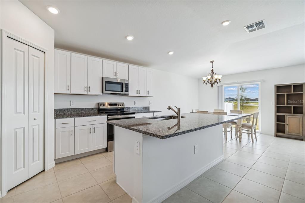 A kitchen with white cabinets, granite countertops, a center island, and an adjacent dining area — 4530 COZY CONDOR COURT, BARTOW, FL