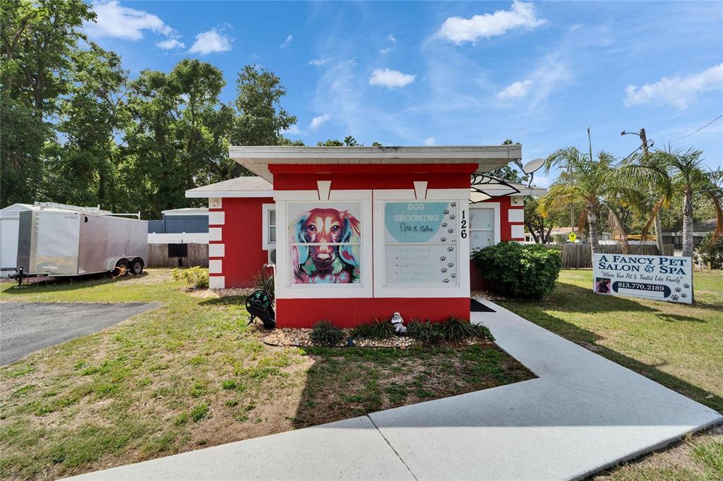 A red and white commercial building with a dog grooming sign and a trailer nearby — 126 RIDGEWOOD AVENUE, BRANDON, FL