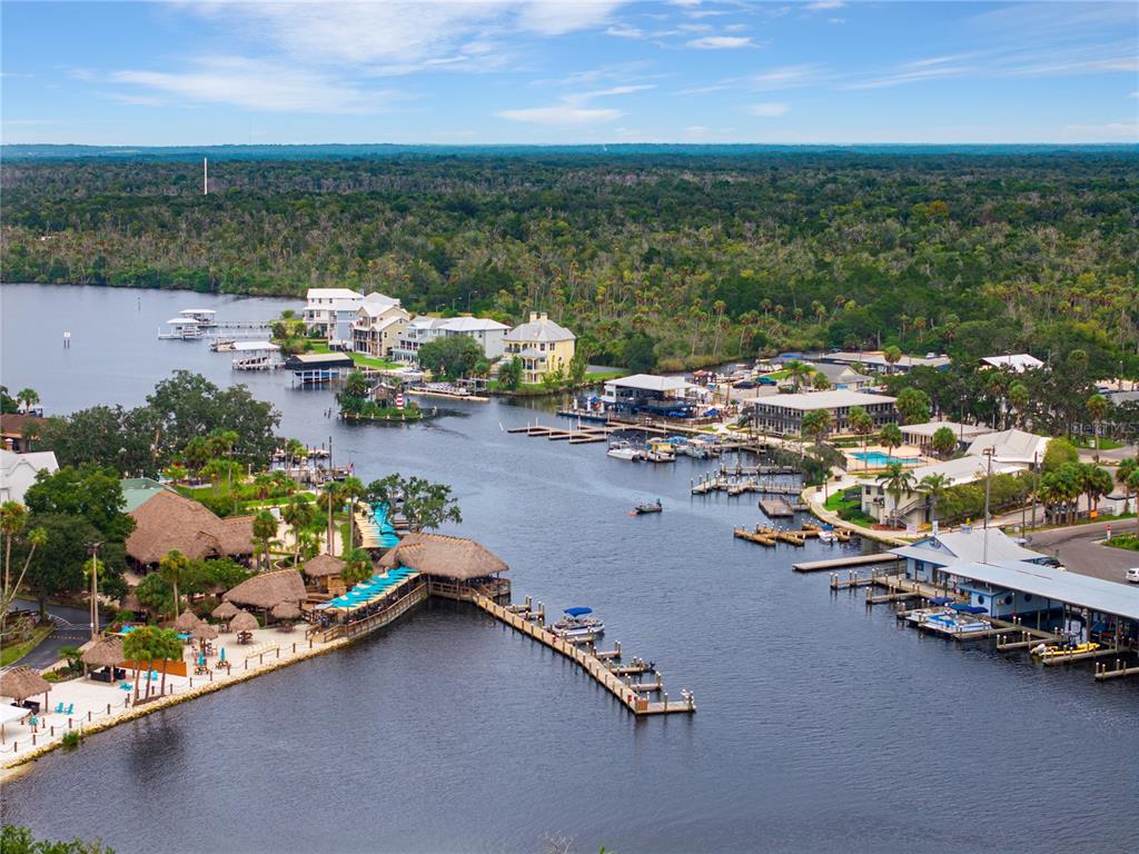 An aerial view shows a riverfront area with docks, boats, and several buildings — 5158 S RIVERVIEW CIRCLE, HOMOSASSA, FL