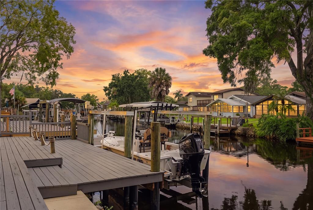A wooden boat dock overlooks a canal with a parked motorboat at sunset — 5158 S RIVERVIEW CIRCLE, HOMOSASSA, FL