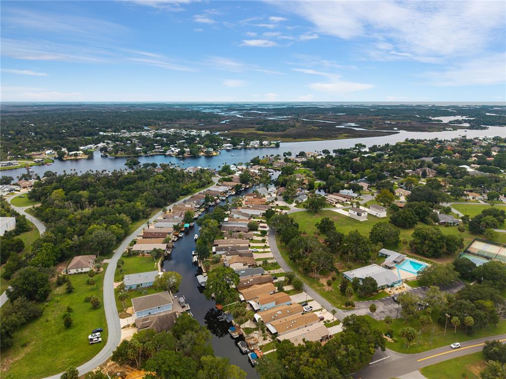 An aerial view shows a residential canal community with houses, boat docks, and surrounding greenery — 5158 S RIVERVIEW CIRCLE, HOMOSASSA, FL