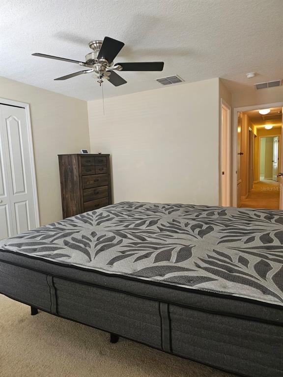 A bedroom features a bed with a patterned mattress, a wooden dresser, and a ceiling fan — 5408 QUARRY ROCK ROAD, LAKELAND, FL