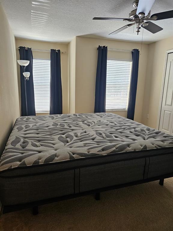 A bedroom features a large mattress on a frame, two windows with dark curtains, and a ceiling fan — 5408 QUARRY ROCK ROAD, LAKELAND, FL