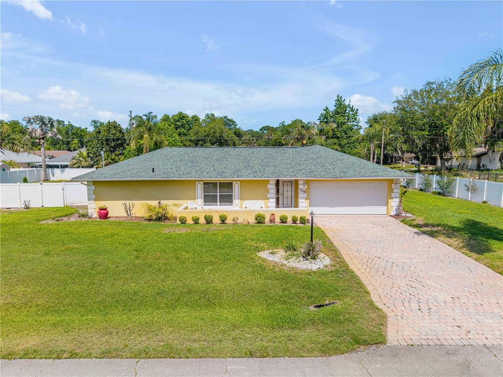 A single-story yellow house with a green roof and a paved driveway — 1529 SABAL PALM DRIVE, EDGEWATER, FL