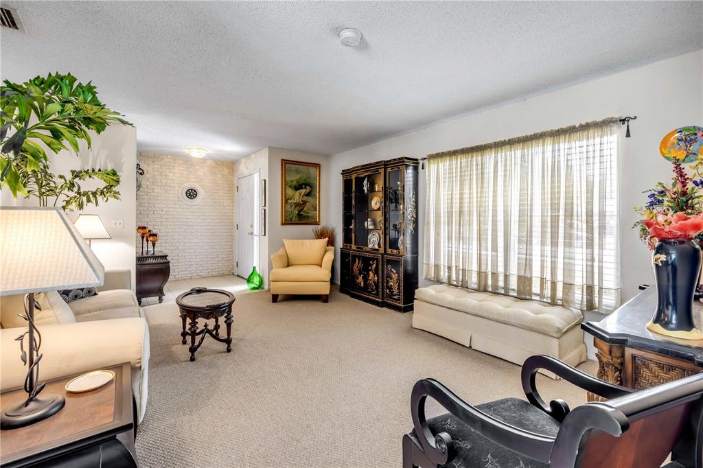 A living room features beige carpeting, a white brick wall, and a black display cabinet — 1529 SABAL PALM DRIVE, EDGEWATER, FL
