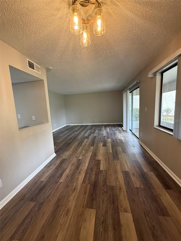 A living room and dining area with wood-look flooring, neutral walls, and a sliding glass door — 737 MIDWAY DRIVE UNIT A, OCALA, FL