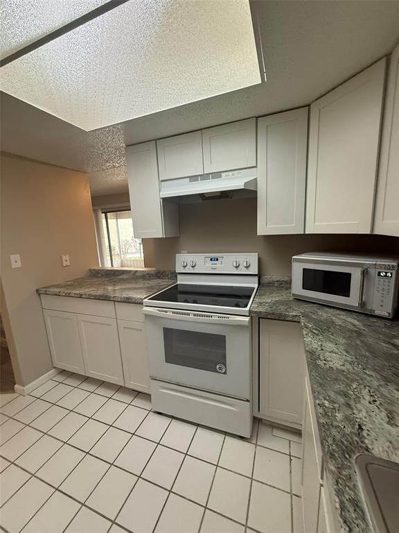 An empty living room features wood-look plank flooring, a textured ceiling, and a sliding glass door — 737 MIDWAY DRIVE UNIT A, OCALA, FL