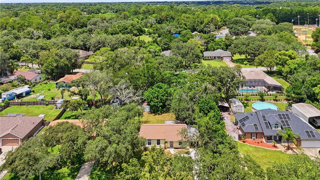An aerial view of a suburban neighborhood featuring several houses, lush trees, and swimming pools — 336 RIVIERA DRIVE, DEBARY, FL