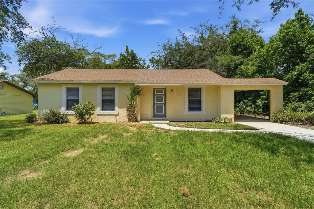 A single-story yellow house with a brown roof, a front door, and an attached carport — 336 RIVIERA DRIVE, DEBARY, FL