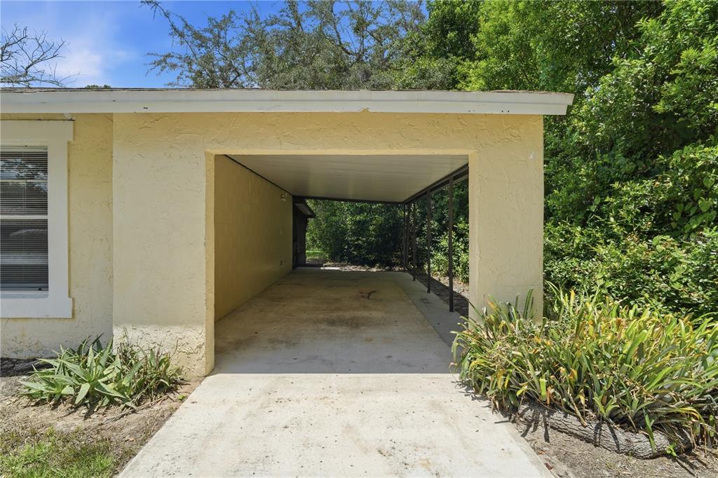 A yellow house features a concrete driveway leading to an open-sided carport — 336 RIVIERA DRIVE, DEBARY, FL