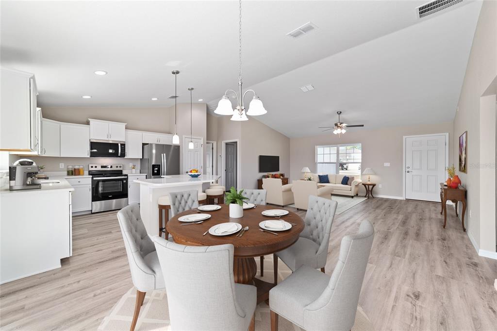 An open-concept kitchen, dining area, and living room featuring light wood floors and white cabinetry — 7830 N JAMAICA DRIVE, CITRUS SPRINGS, FL