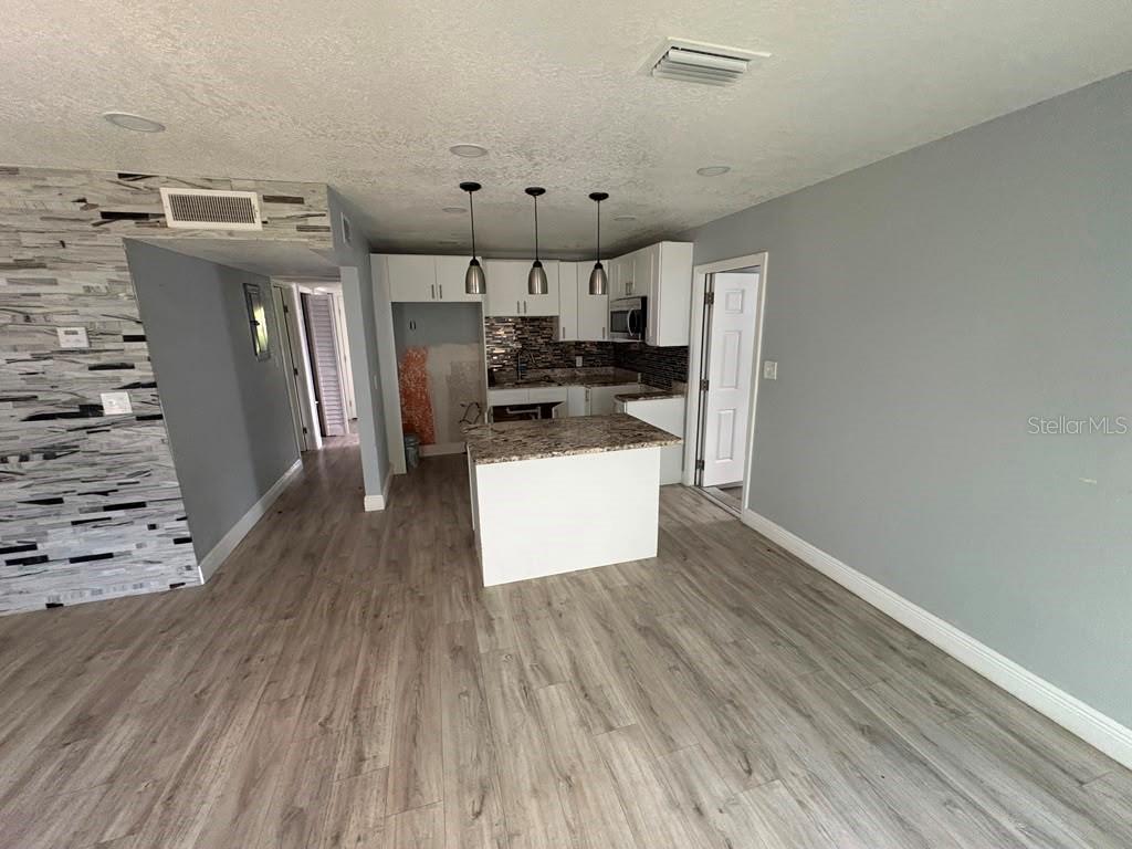 A kitchen with white cabinets and a granite island opens into a living area — 3206 E EMMA STREET, TAMPA, FL