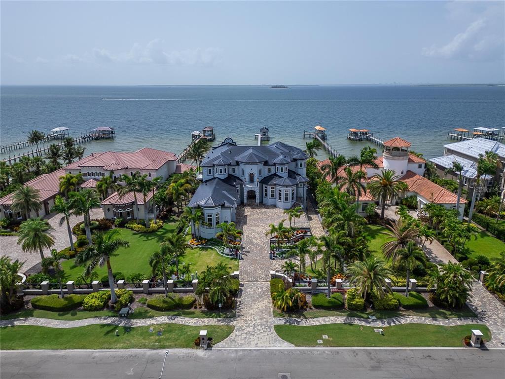 An aerial view shows a large waterfront mansion with a paved driveway and private docks — 6526 SURFSIDE BOULEVARD, APOLLO BEACH, FL